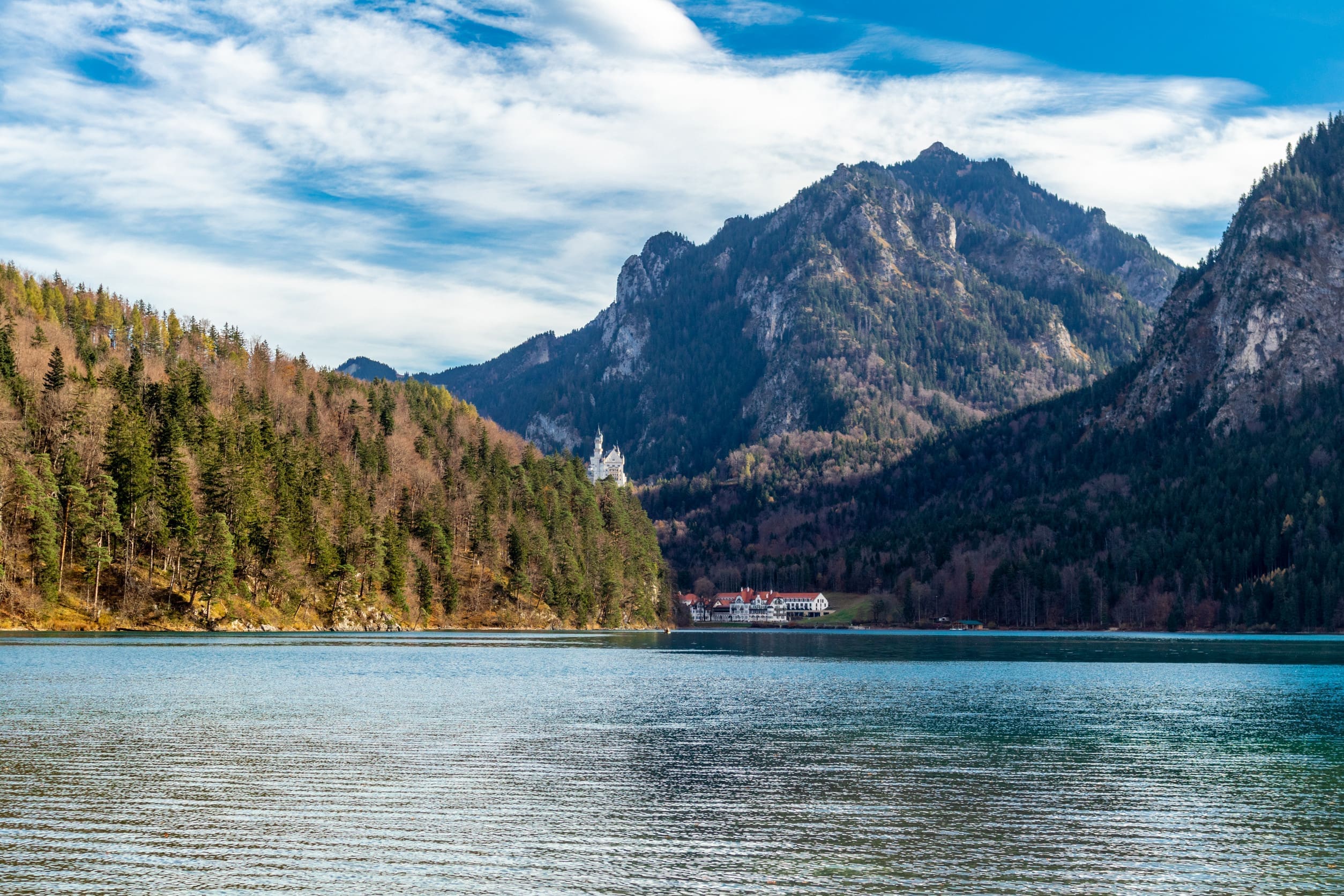 一張廣闊的山地湖泊阿爾卑斯湖，遠處是德國巴伐利亞阿爾卑斯山區的兩座著名城堡-霍恩施旺高城堡和新天鵝堡。